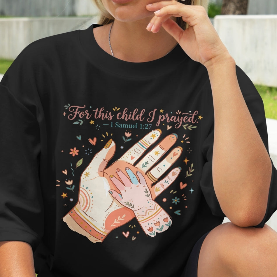 Person wearing a black t-shirt with a graphic design and text, sitting outdoors.