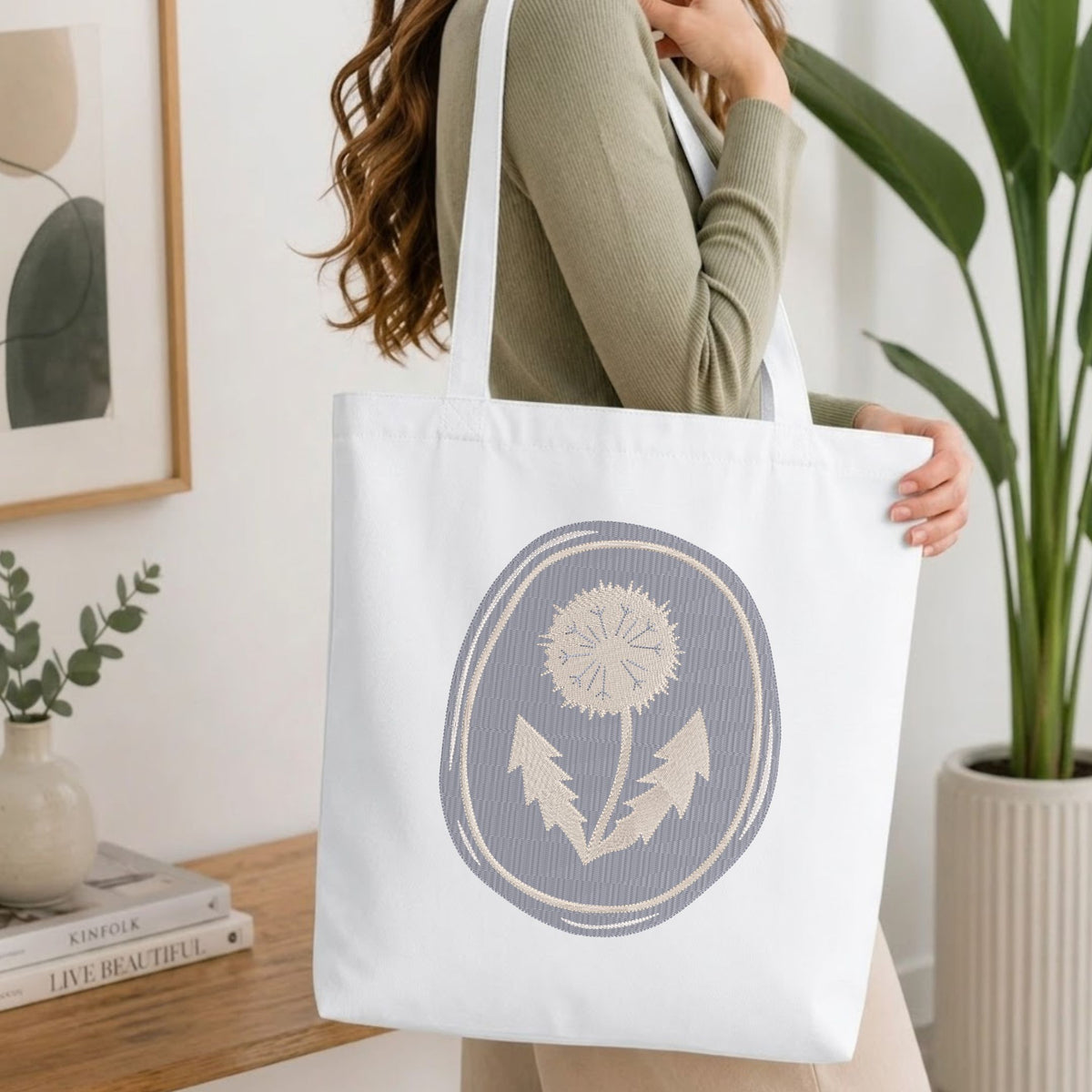  Folded white cotton t-shirt mockup featuring a vintage botanical dandelion machine embroidery design, styled with cotton stems and a wooden cup.   