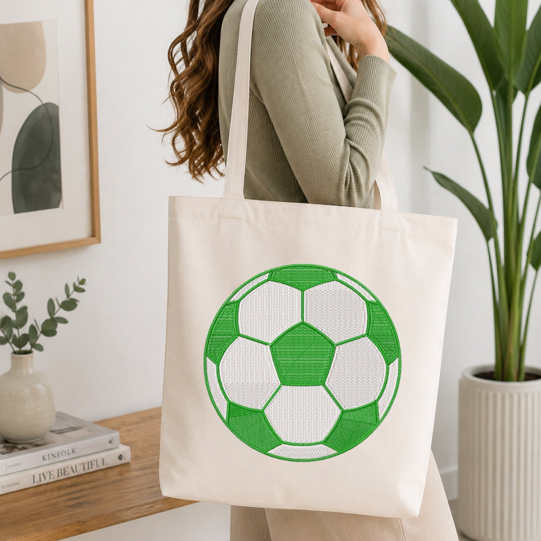Person holding a tote bag with a green and white soccer ball design in a home setting.