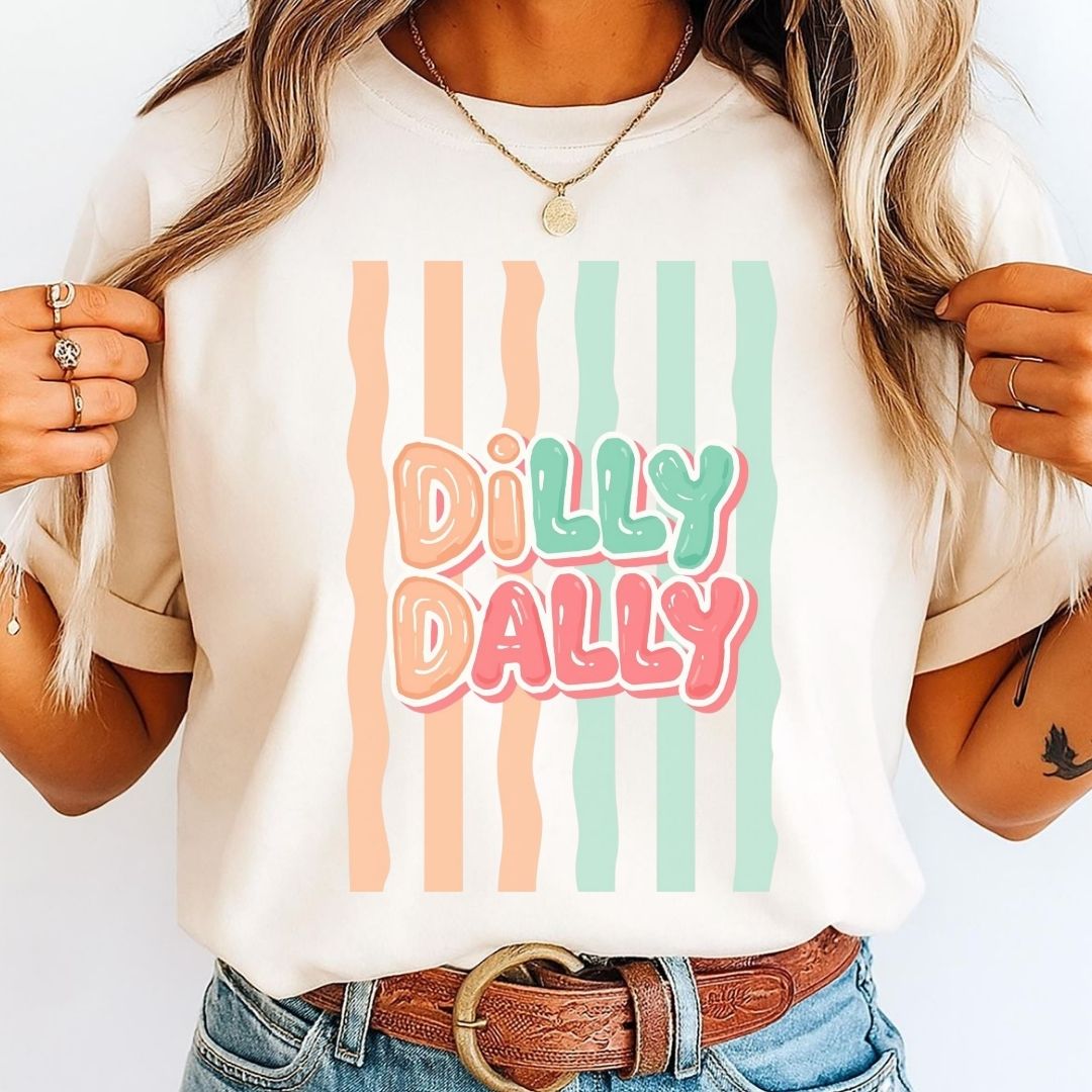 Person wearing a white t-shirt with 'Dilly Dally' text and colorful stripes.