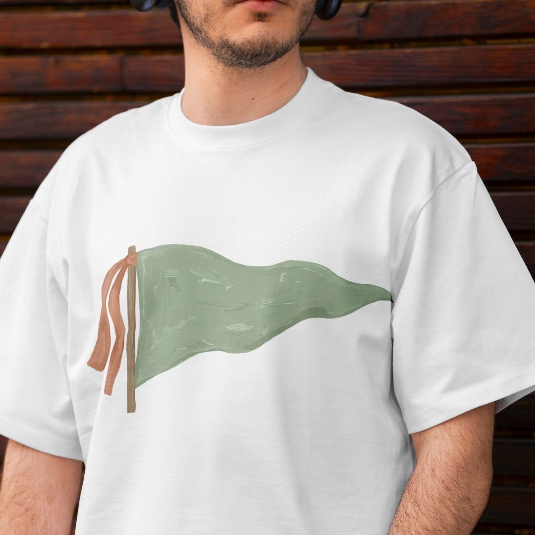 Person wearing a white t-shirt with a green flag design against a wooden background