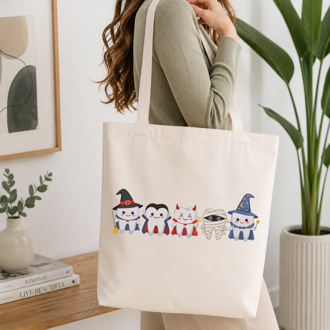  Woman carrying a white natural canvas tote bag featuring a cute Halloween teeth characters machine embroidery design in a bright, modern interior setting   