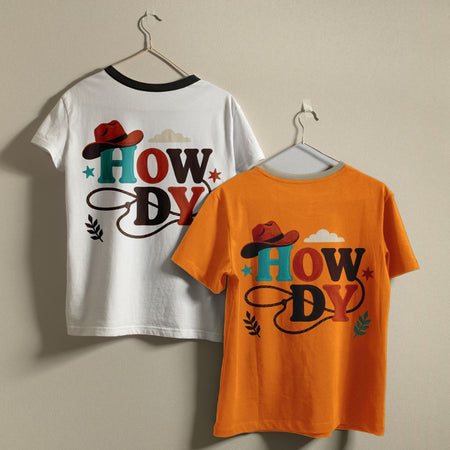 A white ringer t-shirt with a black collar and a solid orange t-shirt hanging on a wall, showcasing the retro cowboy design asset print.