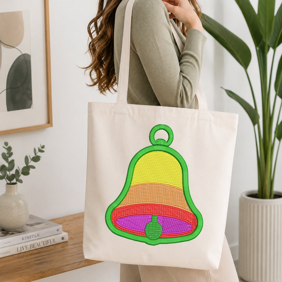 Person holding a tote bag with a colorful bell design in a home setting.