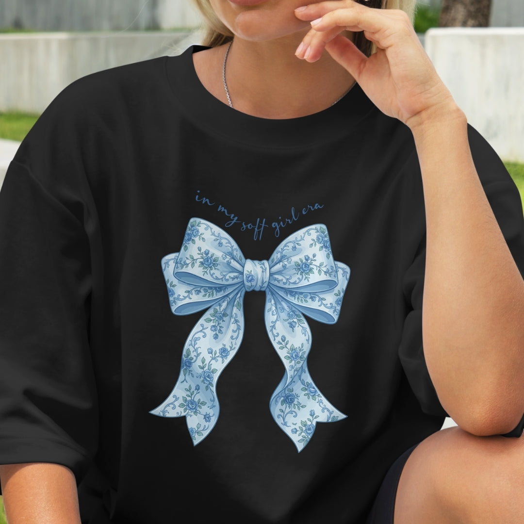 Person wearing a black t-shirt with a blue floral bow design and text.