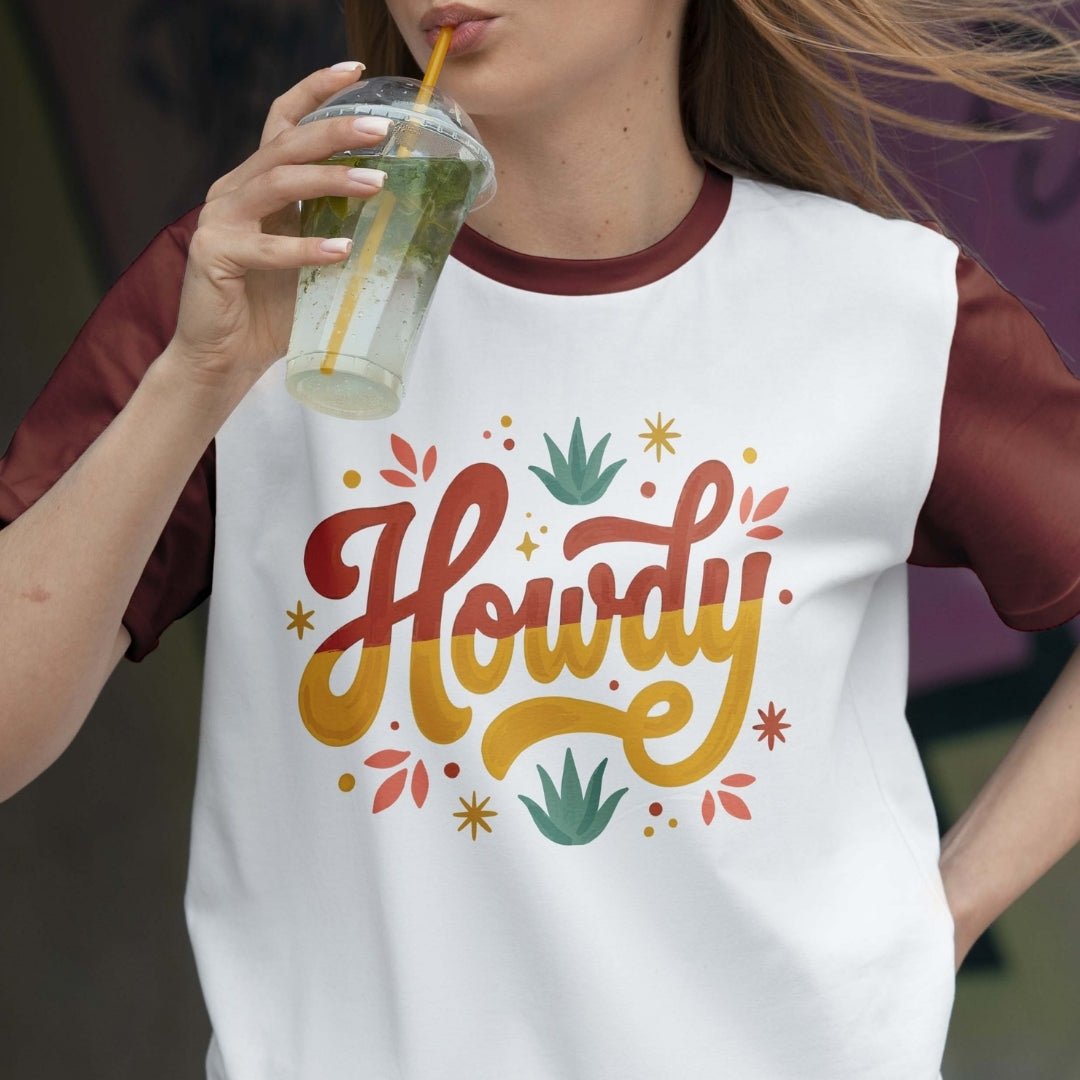 Person wearing a white t-shirt with 'Howdy' design, holding a drink.