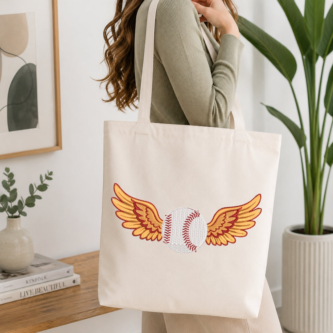 Person holding a tote bag with a baseball and wings design in a home setting.