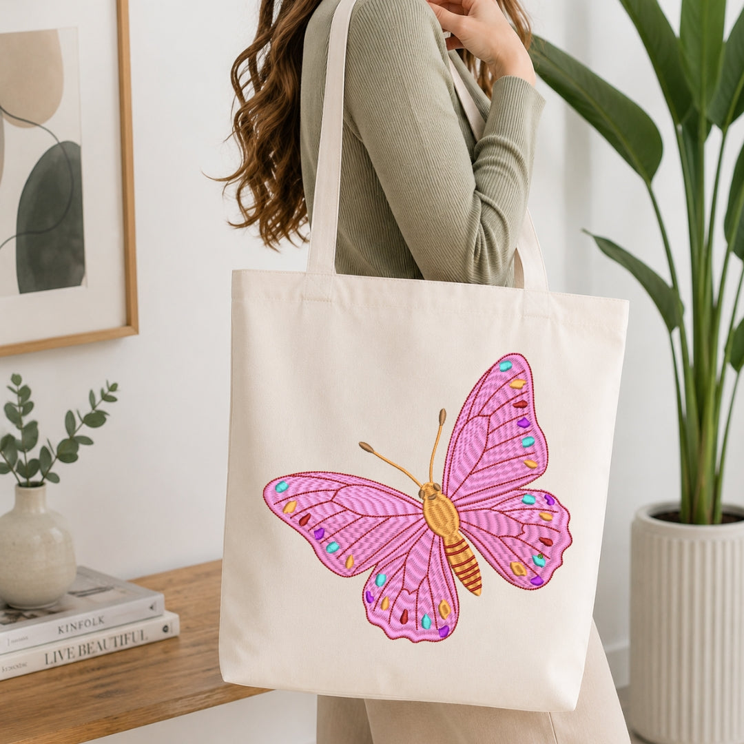 A person carrying a cream-colored canvas tote bag that is decorated with the same pink butterfly embroidery design.