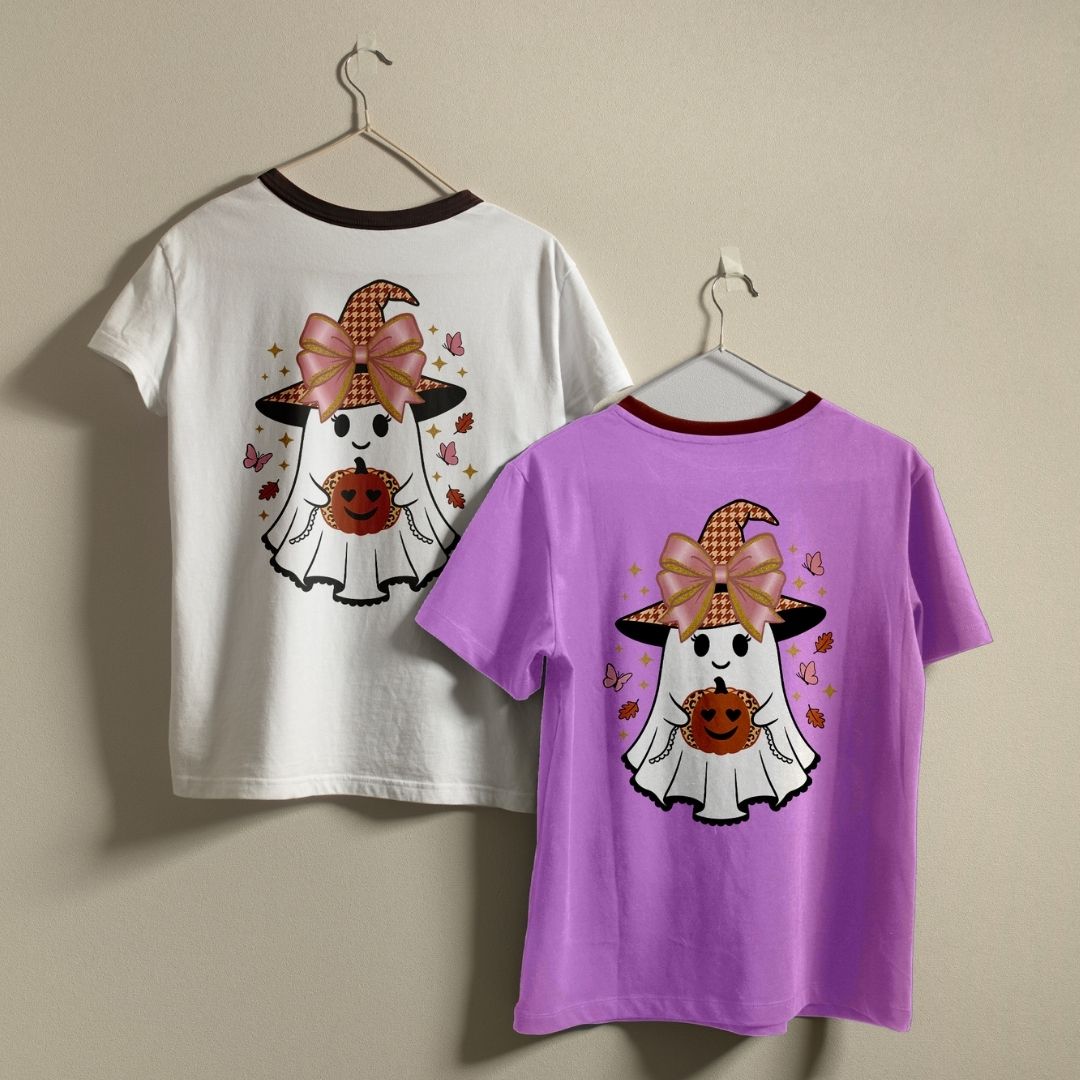 Two children's ringer t-shirts hanging on hangers against a beige wall. One shirt is white with a dark red collar and features a Halloween ghost graphic on the back.