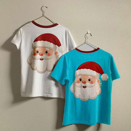 Two children's short-sleeve T-shirts hanging on hangers against a plain beige wall. One shirt is white with a red collar and features a large Santa Claus face graphic on the front.