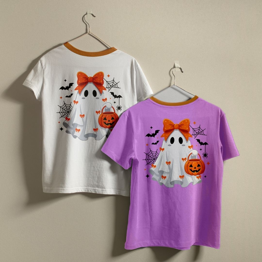 Two t-shirts hanging on a wall—one white and one purple—both displaying the cute Halloween ghost graphic print design.