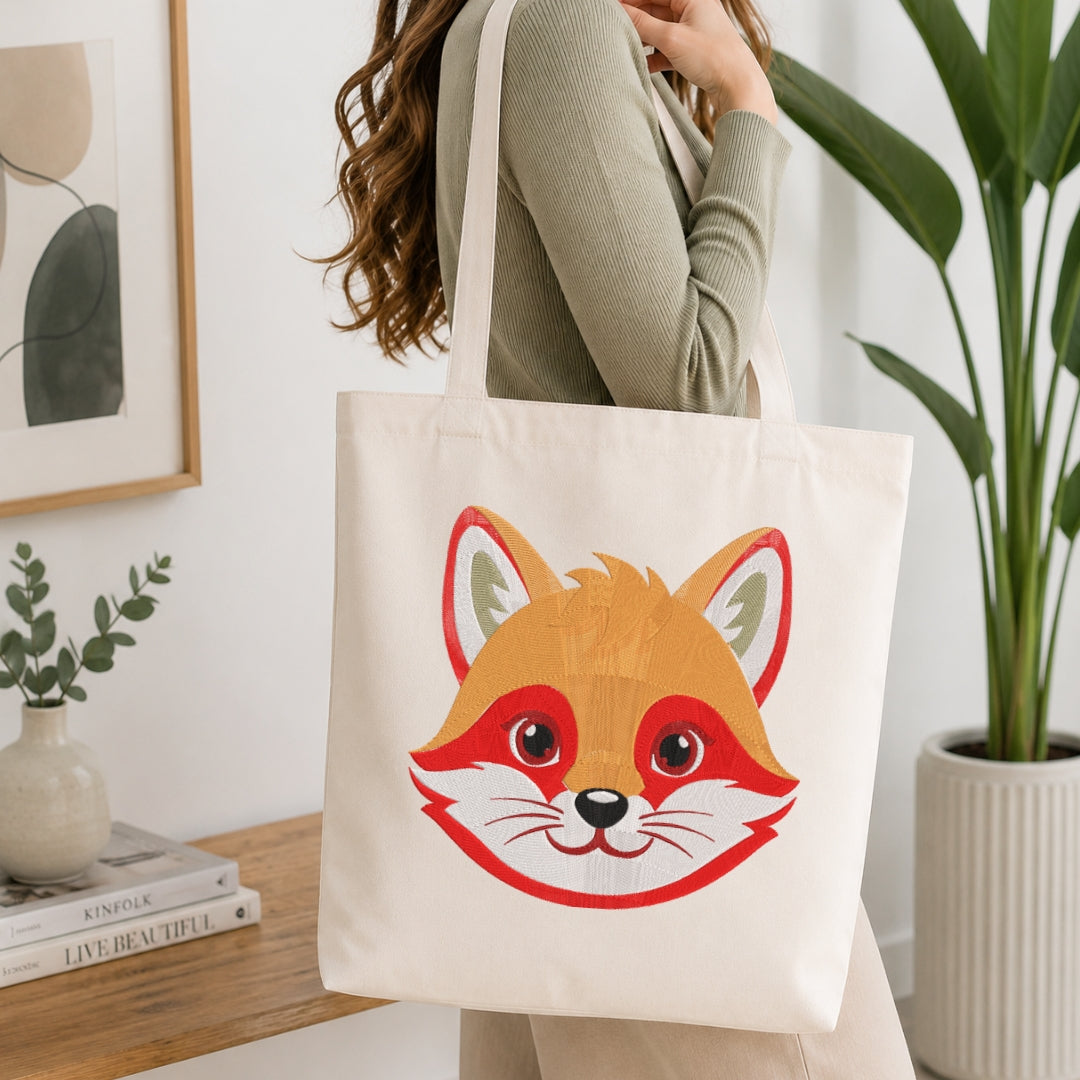 A person carrying a cream-colored tote bag showcasing an embroidered design of a fox's face.