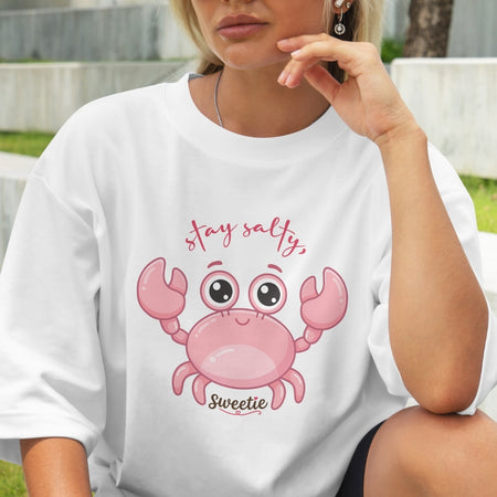 Person wearing a white t-shirt with a pink crab graphic and text.