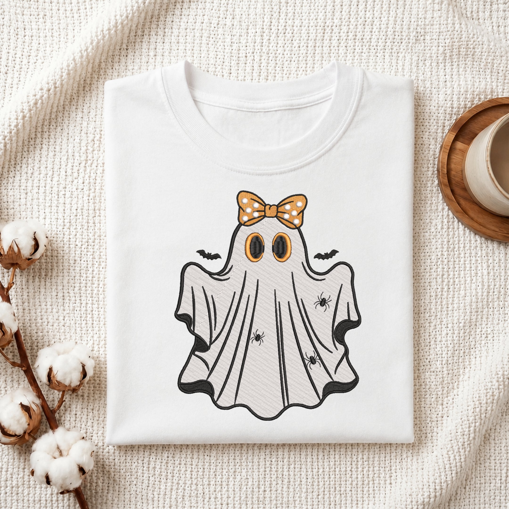 Folded white t-shirt mockup with a cute ghost embroidery design wearing a polka dot hair bow.
