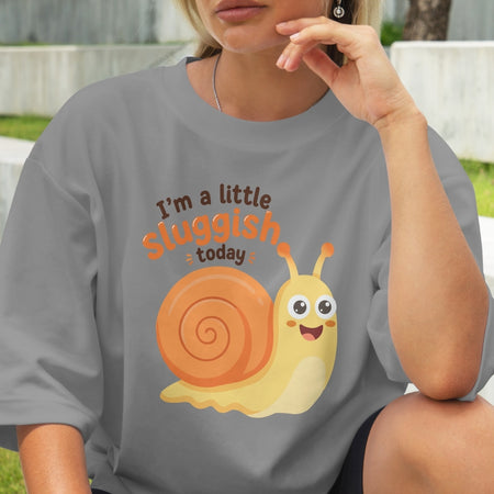 Person wearing a gray t-shirt with a cartoon snail and text 'I'm a little sluggish today'.