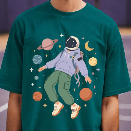 Person wearing a green t-shirt with an astronaut graphic and space-themed design.