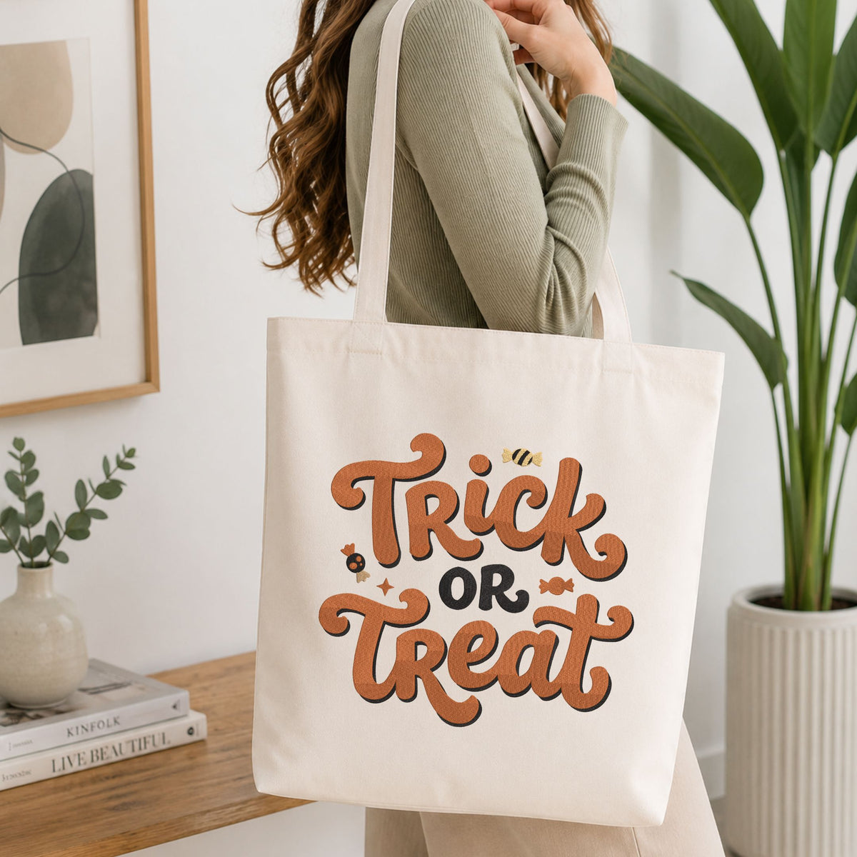  Woman carrying a white natural canvas tote bag featuring a "Trick or Treat" candy machine embroidery design in a bright, modern interior setting   