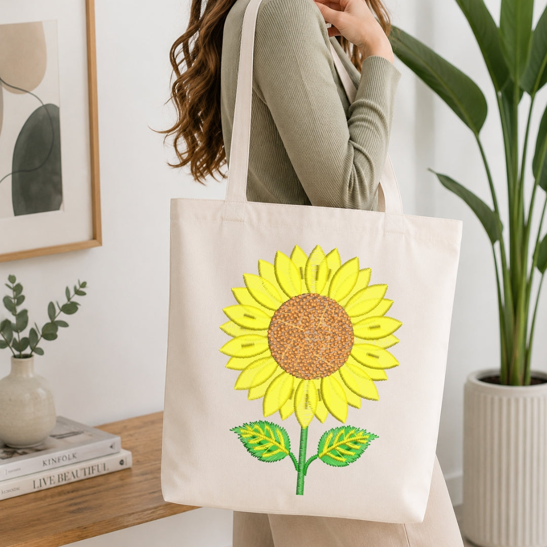 A person carrying a canvas tote bag decorated with the embroidered sunflower design.