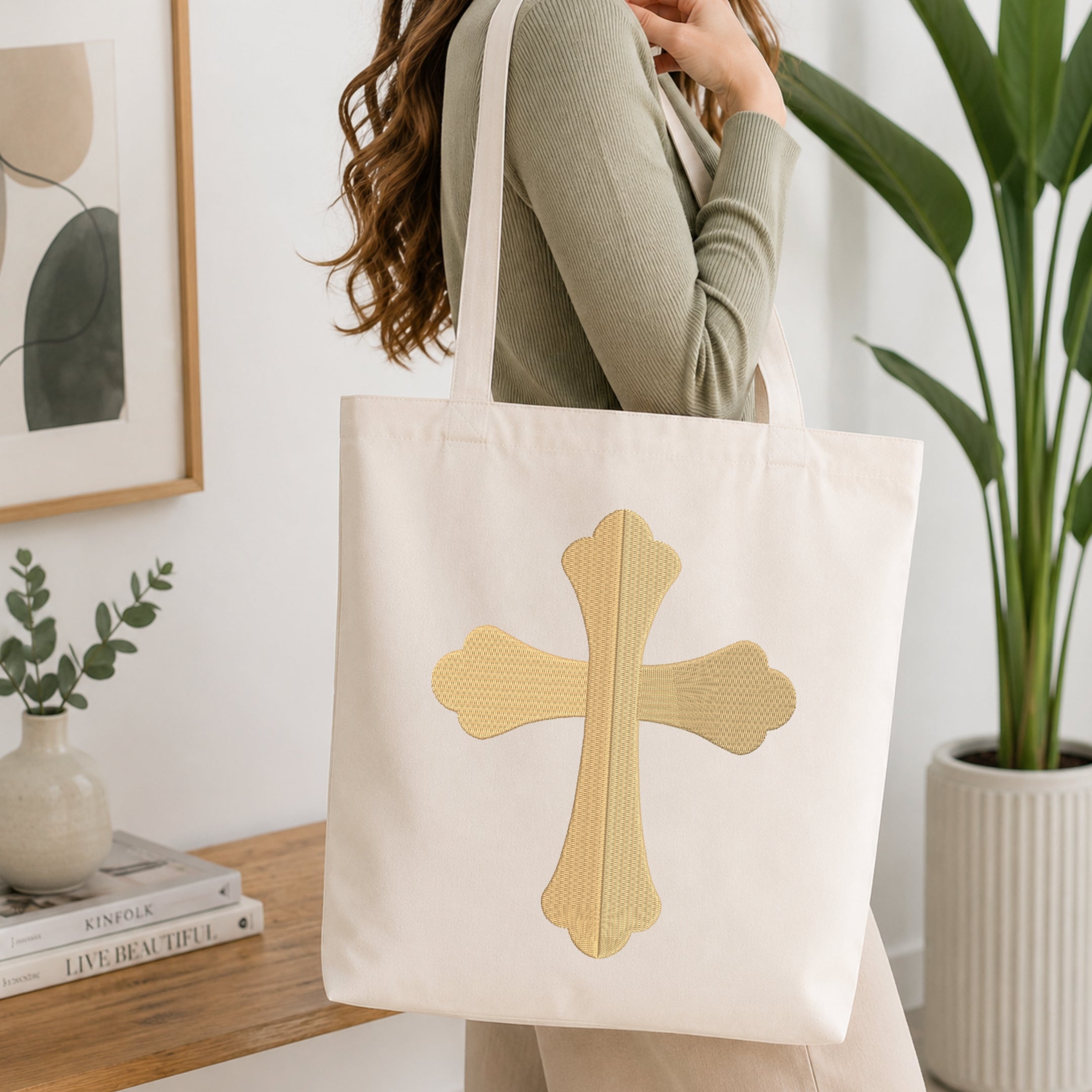 Woman carrying a beige canvas tote bag customized with a solid gold elegant cross embroidery design.