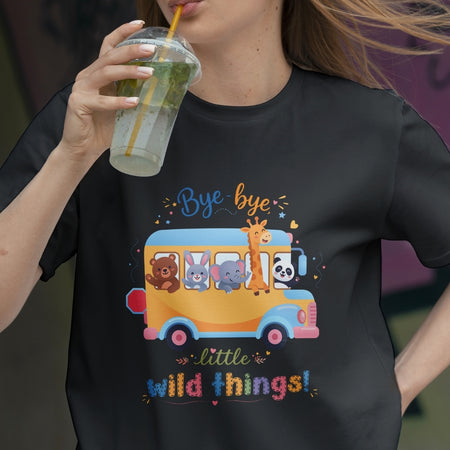 Person wearing a black t-shirt with a colorful bus design and text, holding a drink.