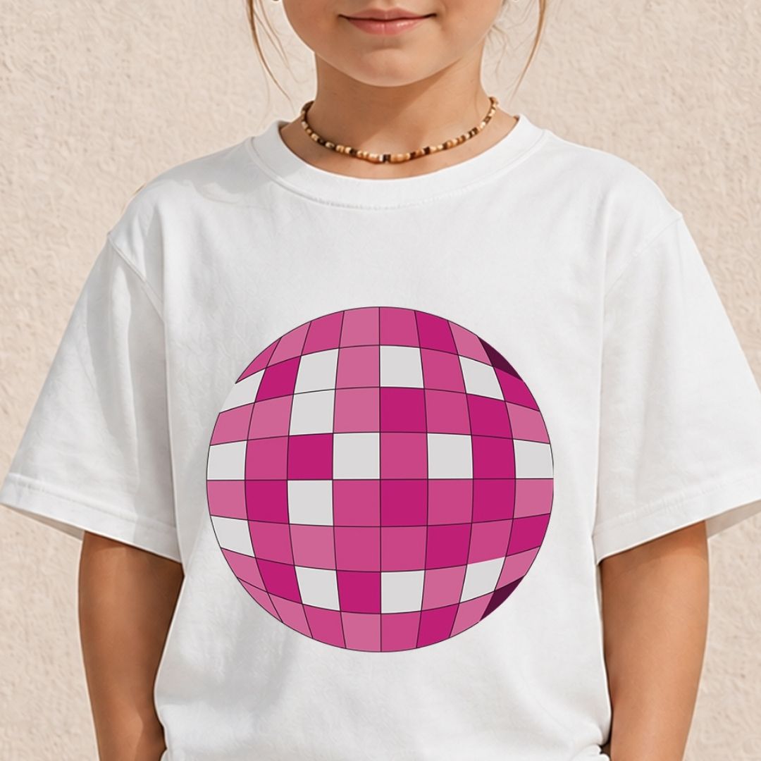 A child wearing a white short-sleeve t-shirt with a large pink and white checkered disco ball graphic on the front, set against a light beige textured wall.