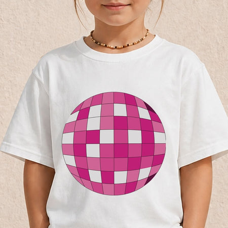 A child wearing a white short-sleeve t-shirt with a large pink and white checkered disco ball graphic on the front, set against a light beige textured wall.