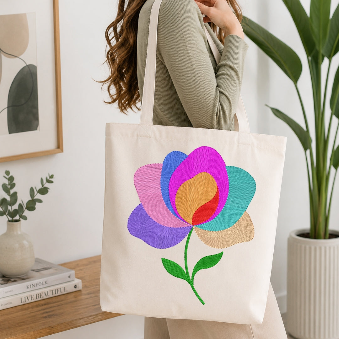 Person holding a tote bag with a colorful flower design in a home setting.