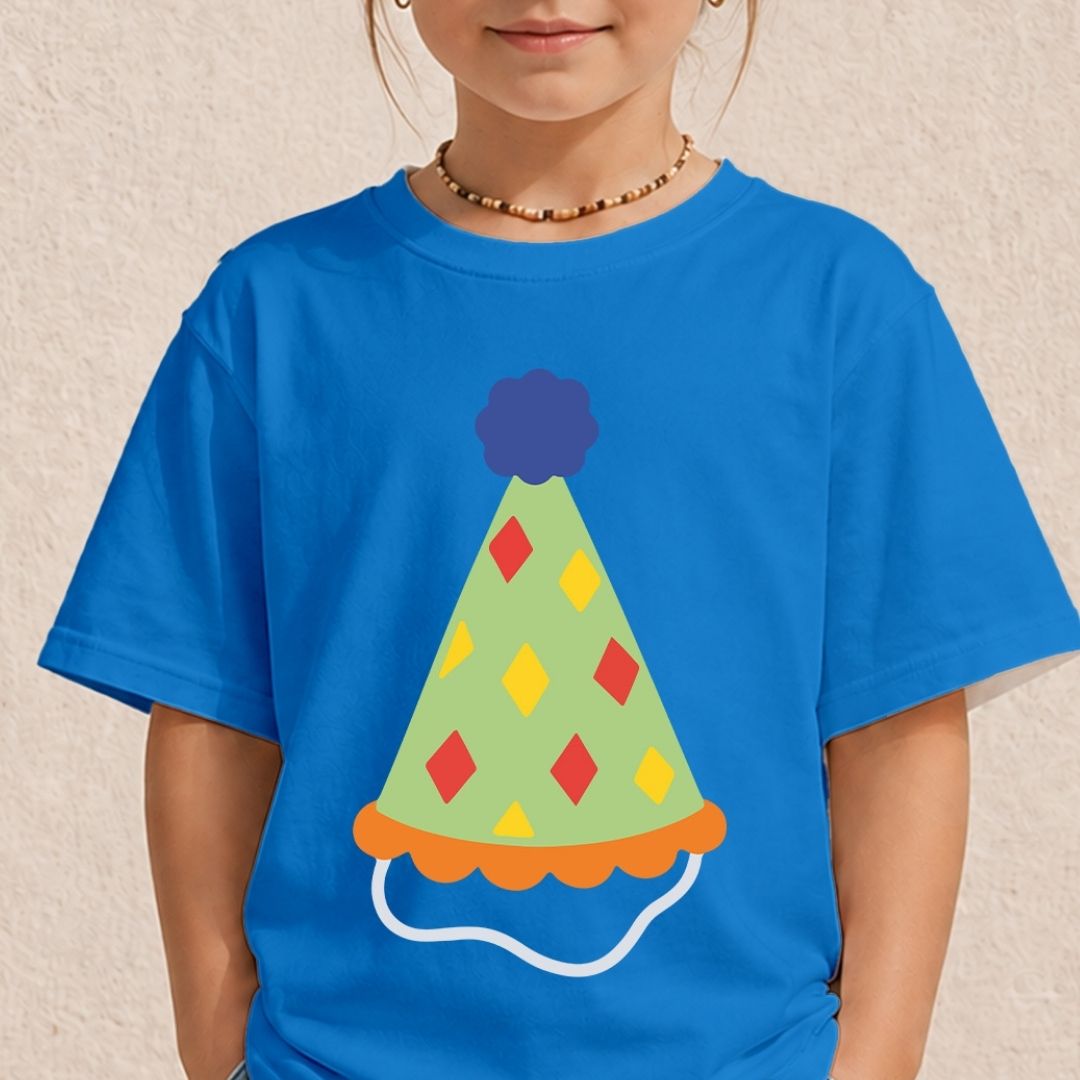 A young girl wearing a bright blue t-shirt printed with a light green party hat featuring red and yellow diamond patterns and a blue pom-pom.