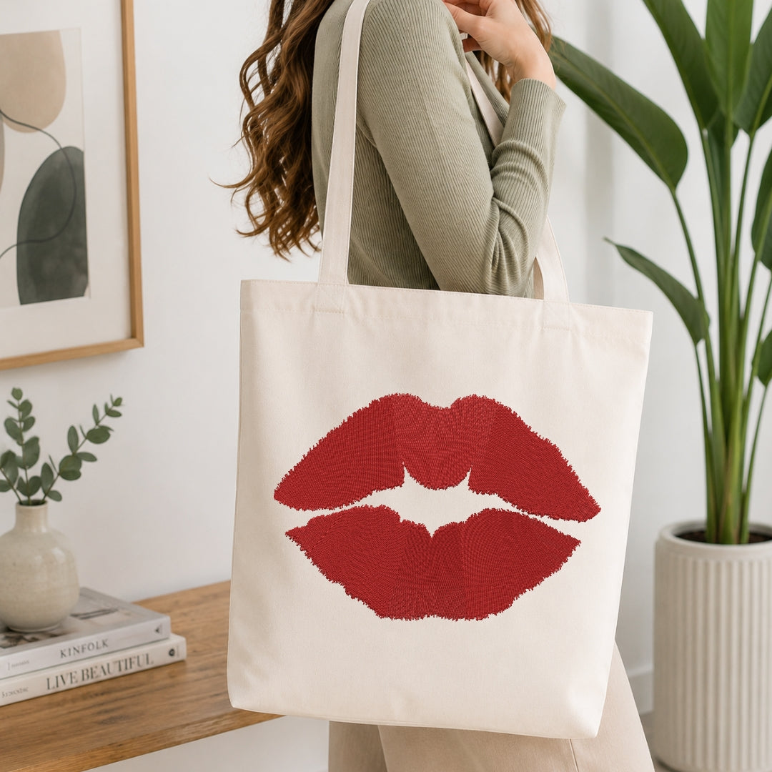 A person carrying a cream-colored canvas tote bag decorated with the embroidered red lips design.