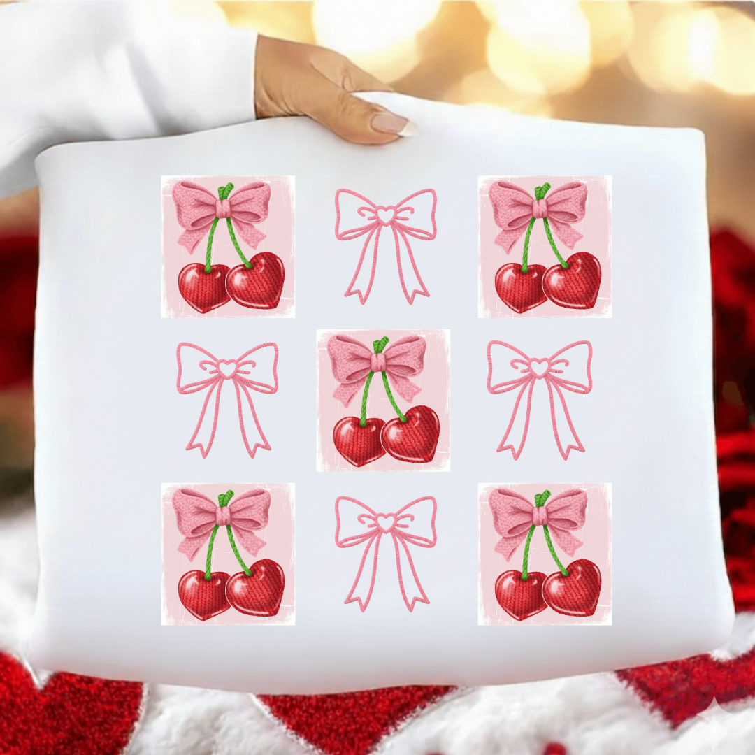 White pillow with red cherries and pink bows pattern held by a person against a blurred background