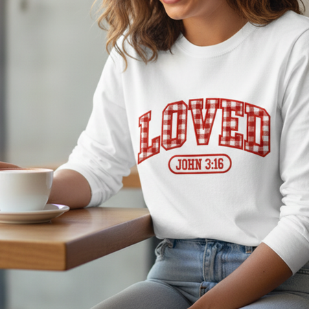 Person wearing a white sweatshirt with red text sitting at a table with a cup.
