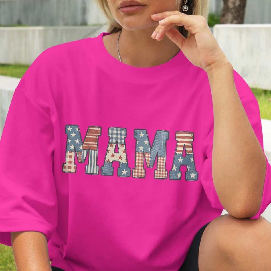 Person wearing a pink t-shirt with 'MAMA' printed in colorful letters.