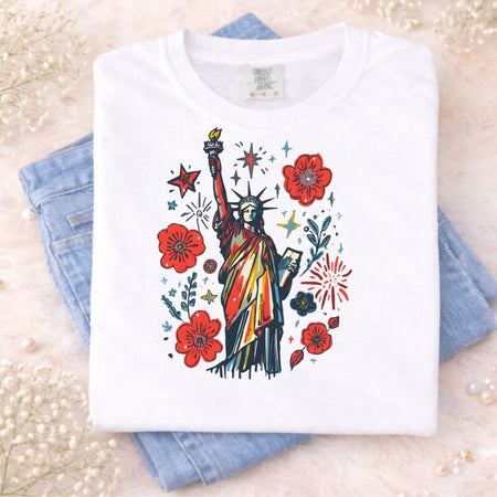 White t-shirt with colorful graphic of the Statue of Liberty and flowers on a light background