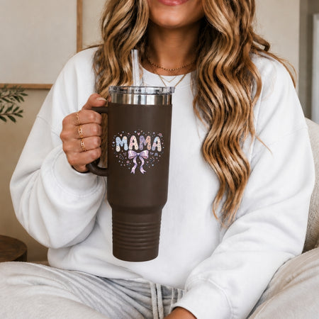 Person holding a brown travel mug with 'MAMA' and a bow design.
