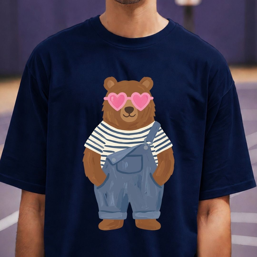 Navy blue t-shirt with a bear wearing sunglasses and overalls on a blurred indoor background