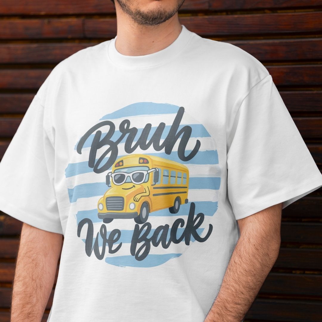 Person wearing a white t-shirt with a yellow school bus graphic and text 'Bruh We Back' against a wooden background.