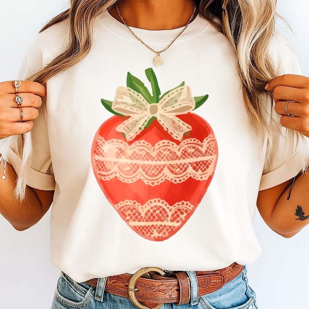 Model wearing a cream white t-shirt styled with a vintage lace-trimmed strawberry clip art graphic.