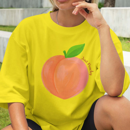 Person wearing a yellow t-shirt with a peach graphic and text.