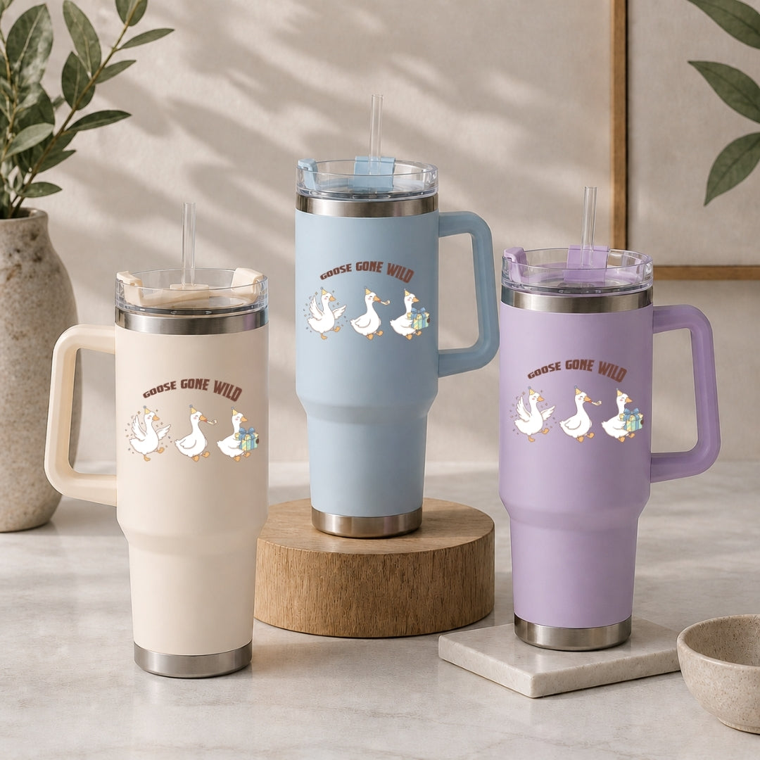 Three insulated tumblers in beige, light blue, and purple, each featuring the fun "GOOSE GONE WILD" geese design.