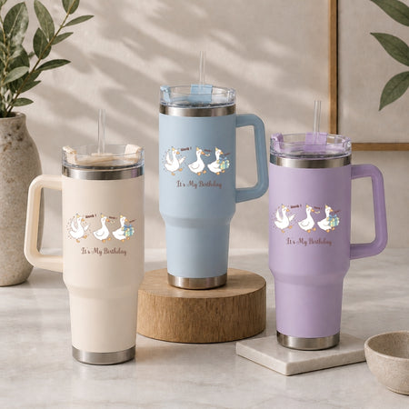 Three insulated tumblers in beige, light blue, and purple, each featuring the fun "It's My Birthday" honking geese design.
