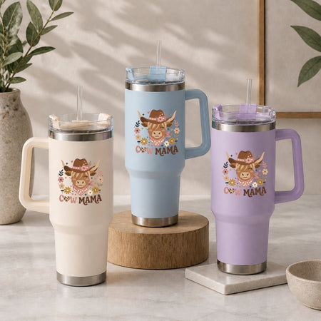 Three insulated travel mugs with cow mom design on a neutral background