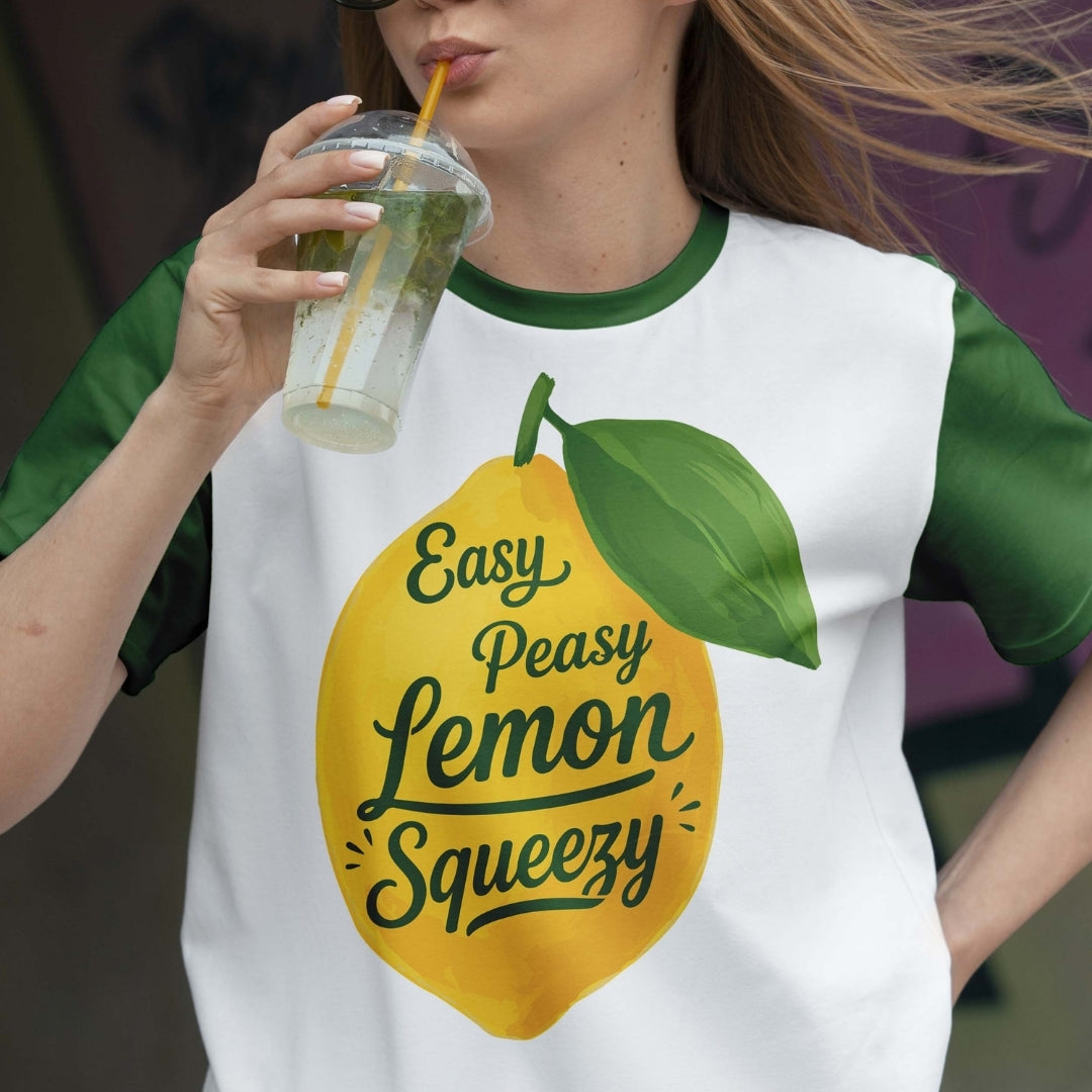 Person wearing a t-shirt with a lemon graphic and text, holding a drink.