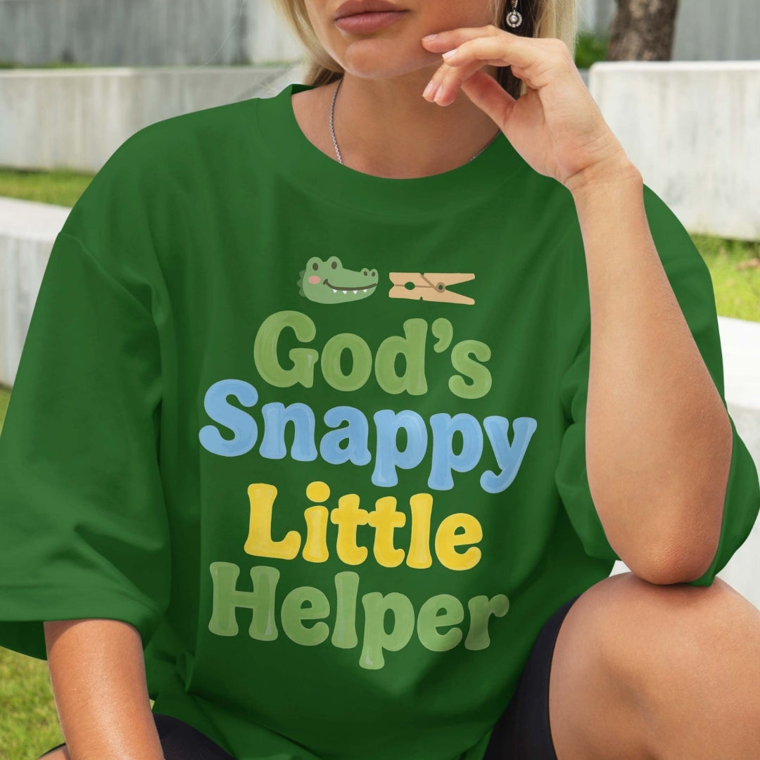 Person wearing a green t-shirt with 'God's Snappy Little Helper' text and graphic.