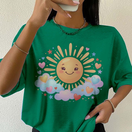 Person wearing a green t-shirt with a sun and cloud design, holding a phone.