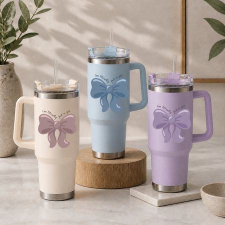 Three insulated tumblers in beige, blue, and purple, each featuring a color-matched bow graphic.