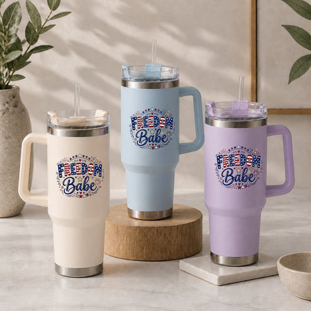 Three insulated travel mugs with 'Freedom Babe' design on a neutral background