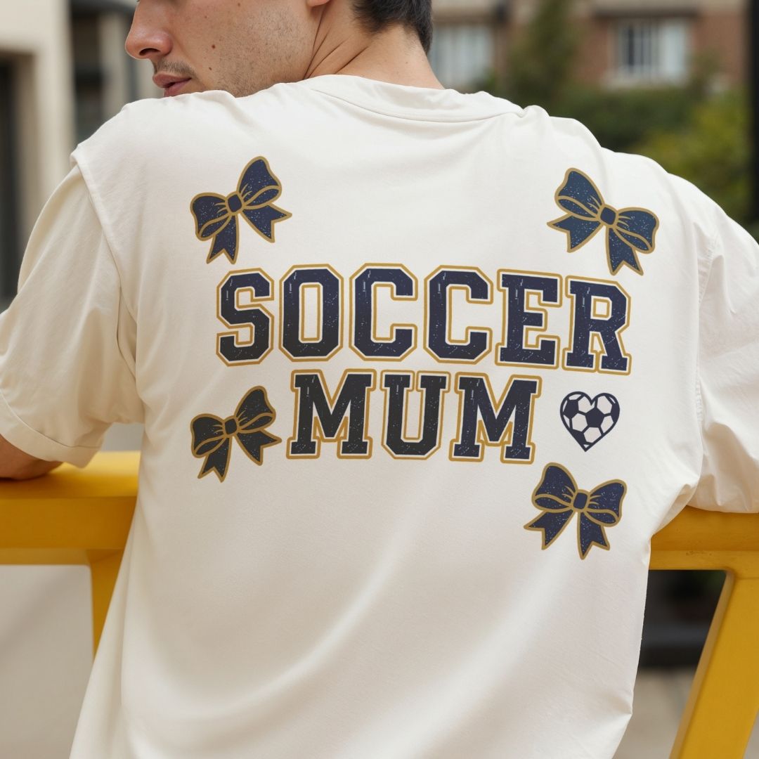 Person wearing a white t-shirt with 'Soccer Mum' text and bow designs.
