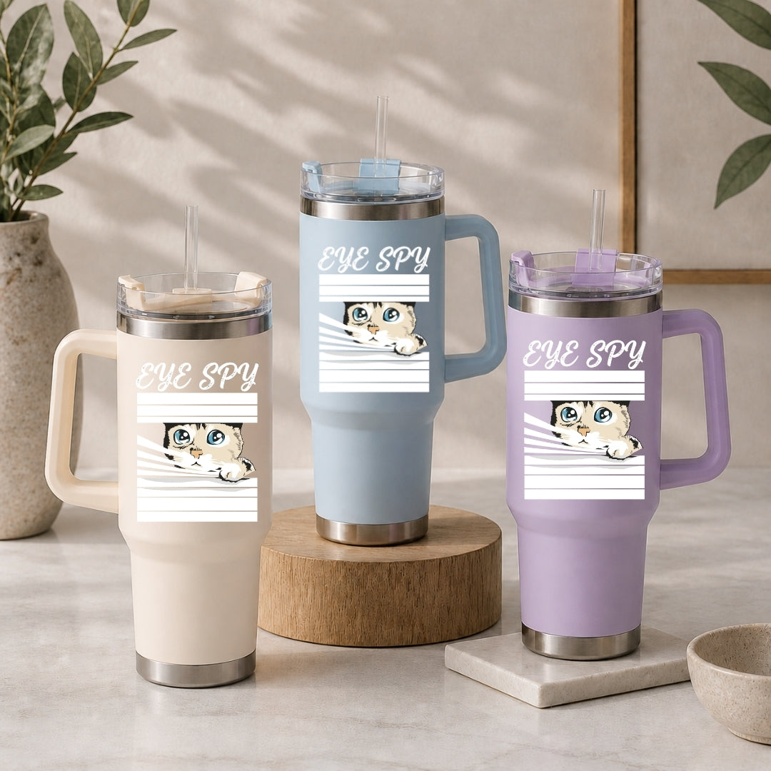 Three insulated travel tumblers with handles and straws in cream, light blue, and pastel purple, all customized with the matching "EYE SPY" peeking cat design.