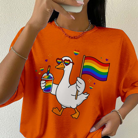 Person wearing an orange t-shirt with a cartoon duck holding a rainbow flag and a drink.