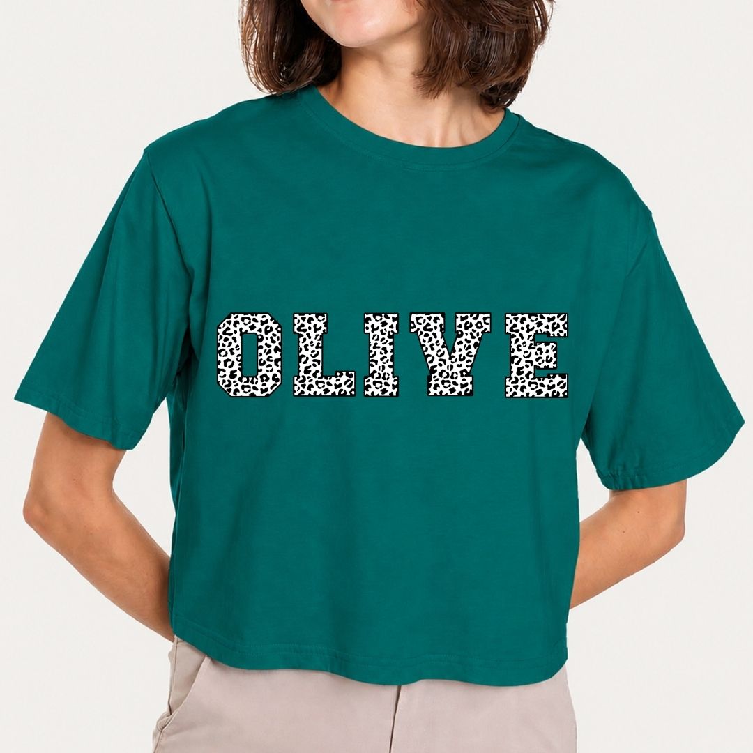 Person wearing a teal t-shirt with 'OLIVE' printed in leopard print.